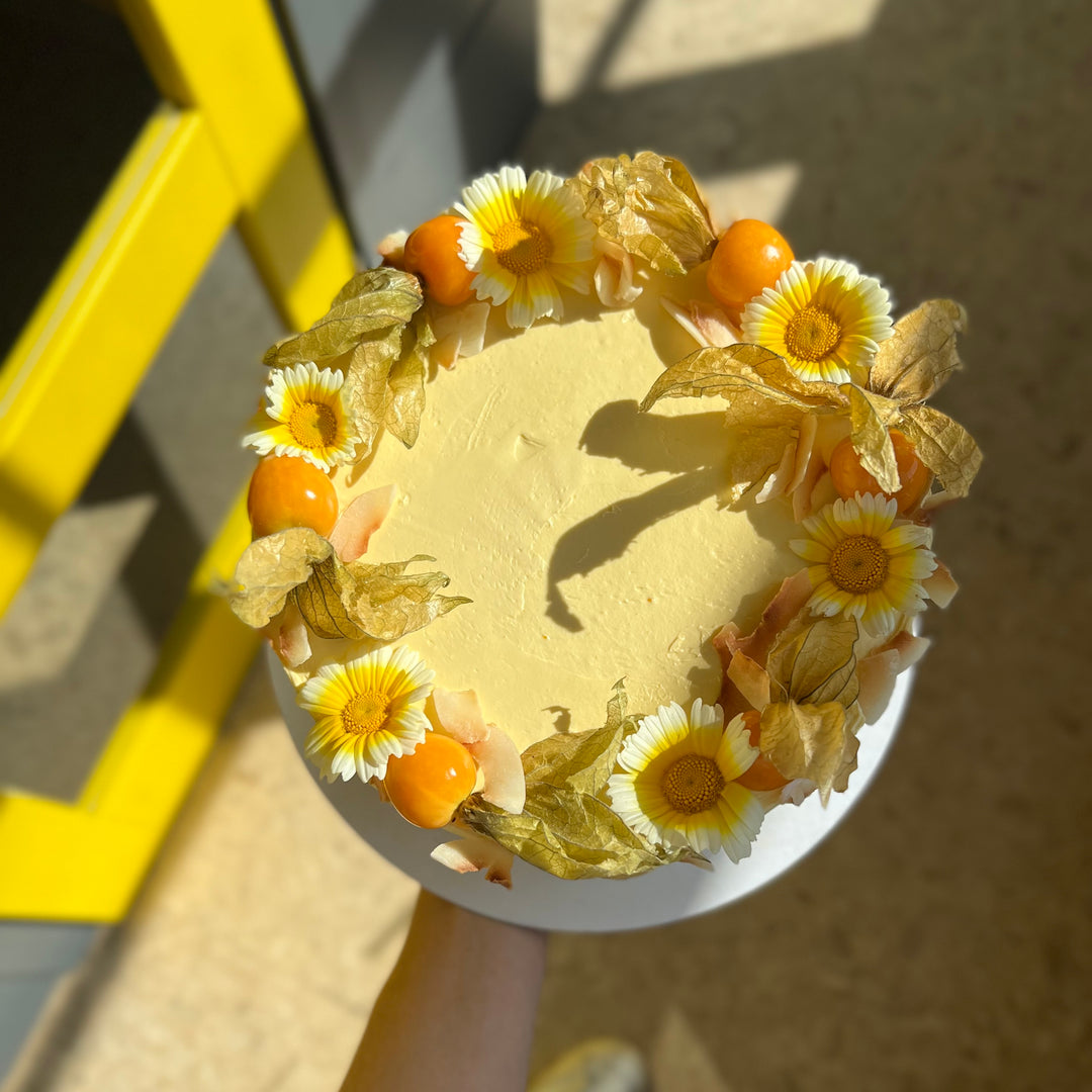 Mango & coconut cake decorated with physalis and daisies, London