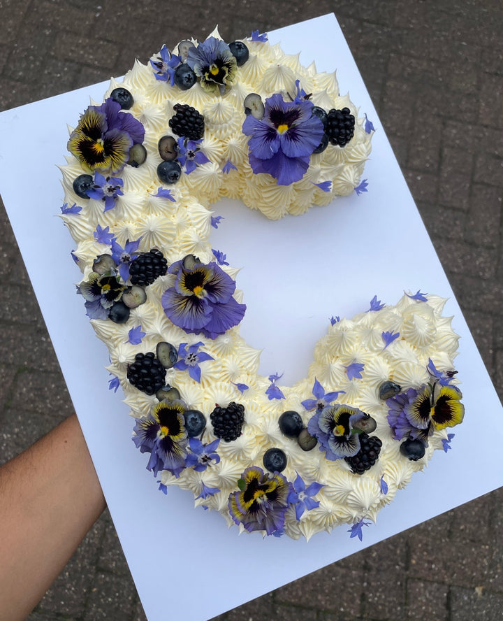 Letter C cake decorated with blackberries and blue flowers. London delivery