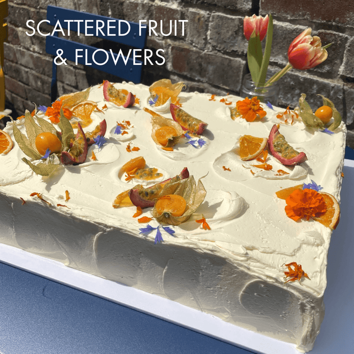 Sheet cake decorated with scattered seasonal fruit and edible flowers