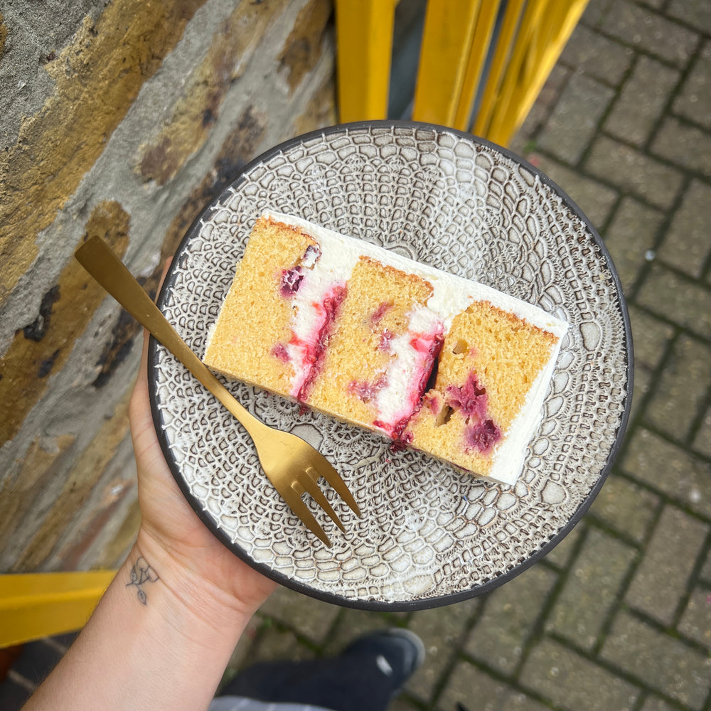 Slice of vanilla & raspberry cake with housemade jam and buttercream layers