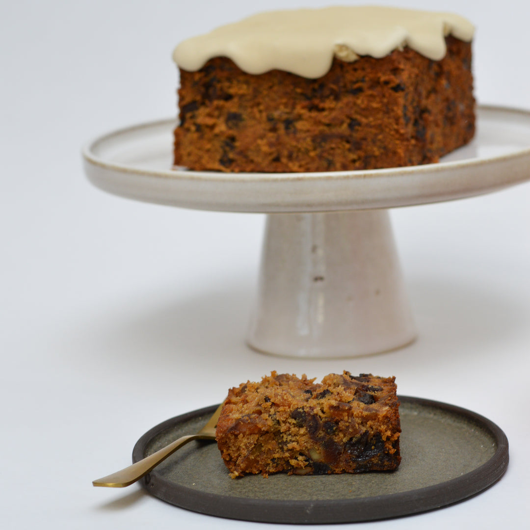 Slice of Christmas cake with iced cake in the background