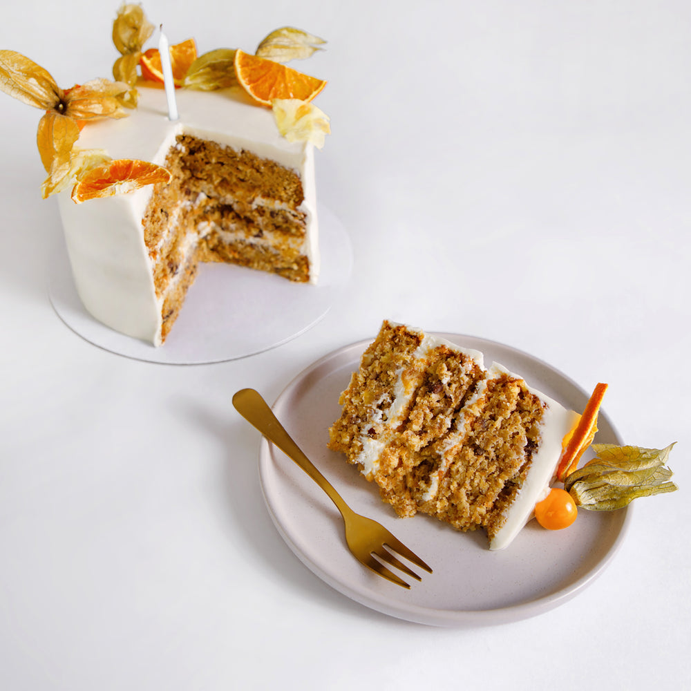 Sunshine cake slice showing banana, carrot and pecan sponge layers with cream cheese icing